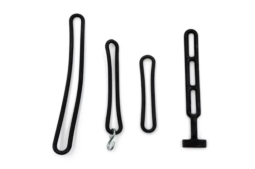 Vier schwarze Gummiartikel in verschiedenen Formen und Größen, darunter Schlaufen und ein Haken, auf einem weißen Hintergrund.