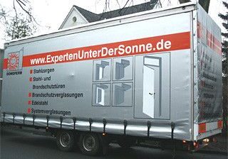 Lkw mit grauem Planenaufdruck, der verschiedene Dienstleistungen und die Website ExpertenUnterDerSonne.de anzeigt.